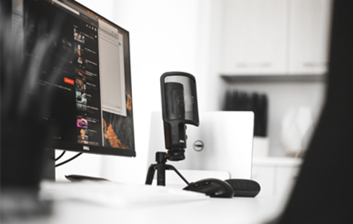 closeup of a monitor and a recording microphone on a desk